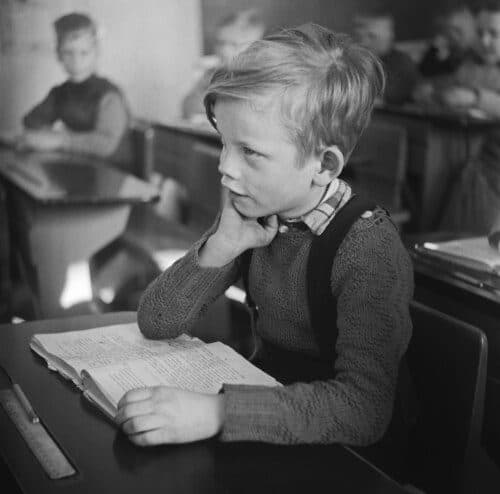 Fotografía de referencia de un niño leyendo en su pupitre