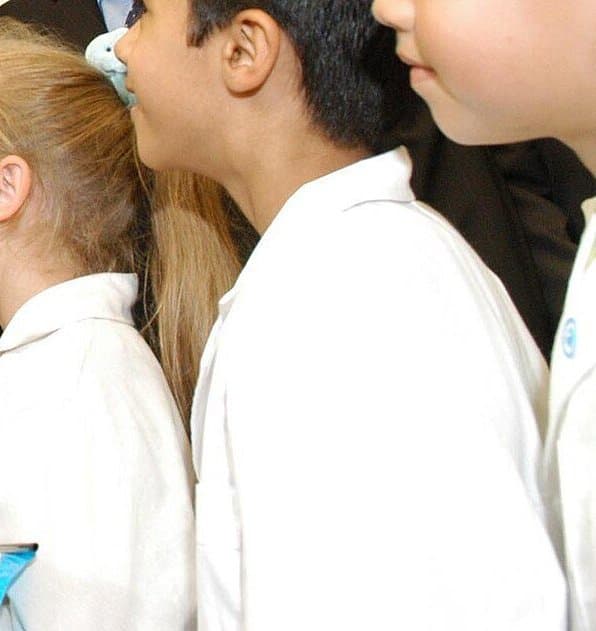Niños con guardapolvo blanco en un acto